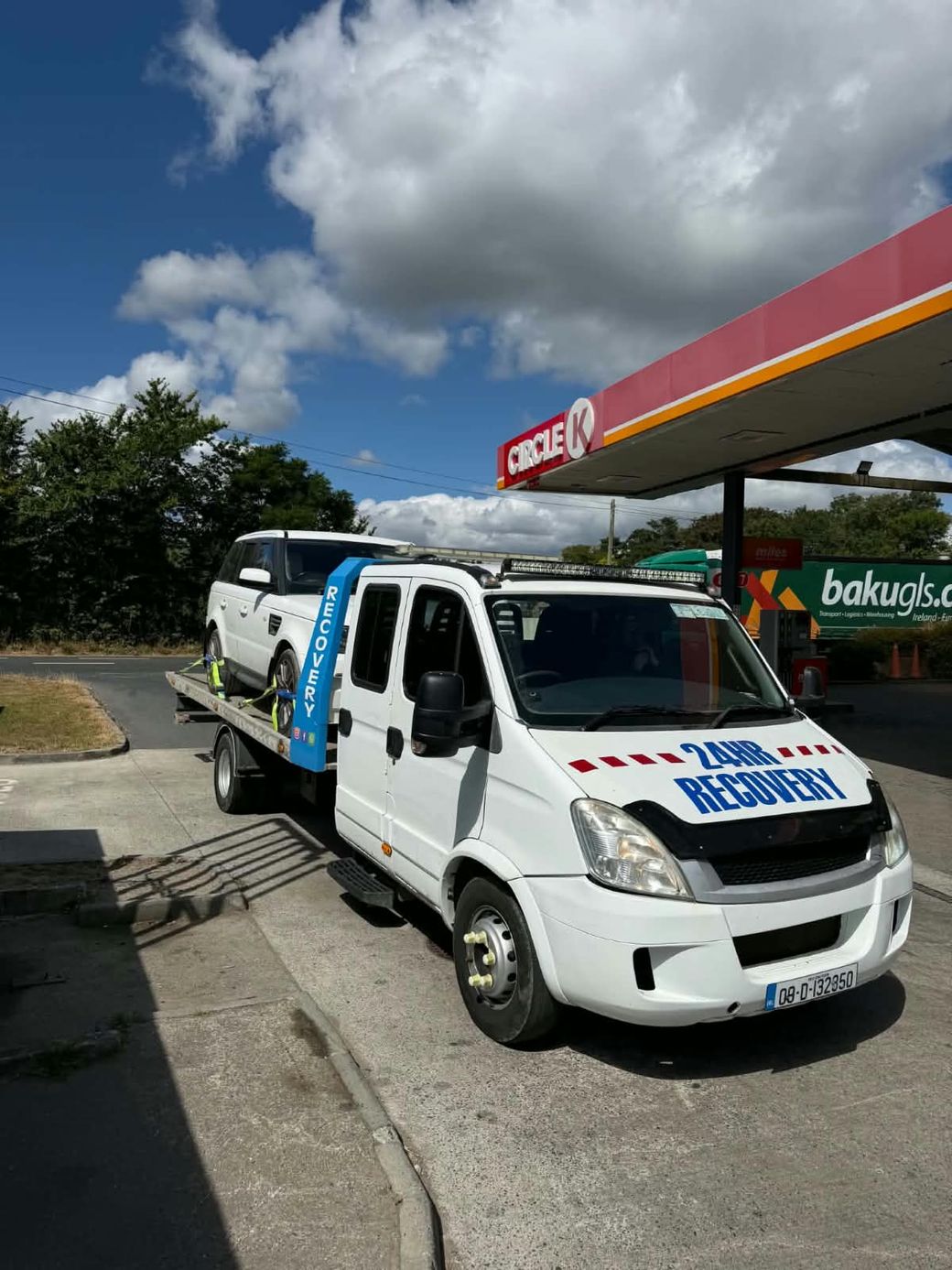 White Range Rover Sport loaded on O'Driscoll's Recovery tilt-and-slide recovery truck at a filling station in Ireland