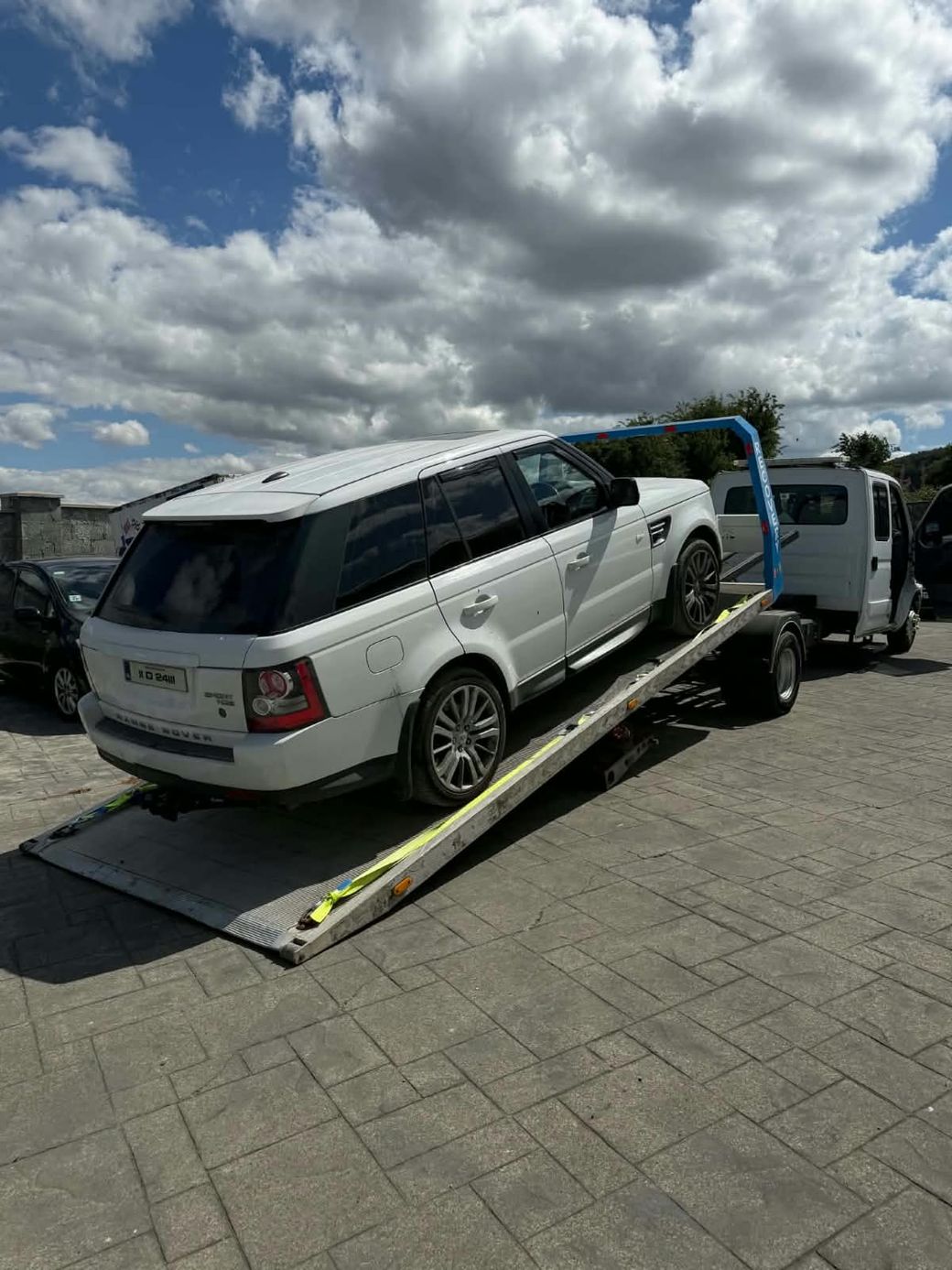 Range Rover Sport being loaded up the tilted flatbed ramp of a recovery truck